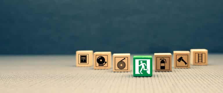 Blocs en bois avec pictogrammes de sécurité incendie erp, dont une sortie de secours verte mise en avant.